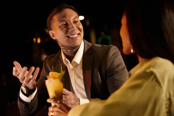 Tattooed young couple shares laughter and drinks during a delightful night out. — Stock Photo