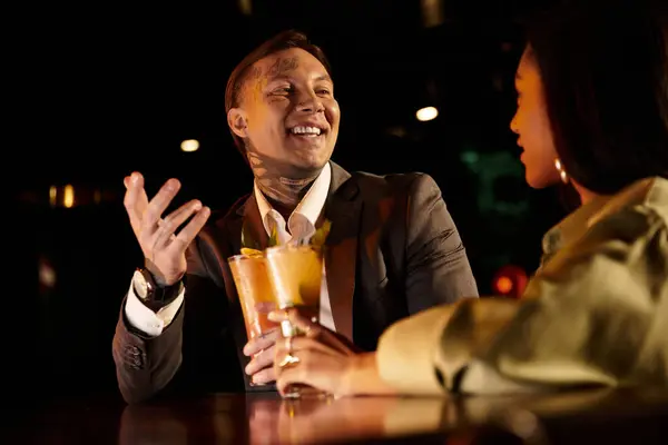 Tattooed man and woman share laughter and drinks while enjoying their evening out together. — Stock Photo