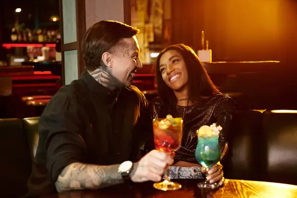 A young couple shares laughter and cocktails while on a delightful night out at a bar. — Stock Photo