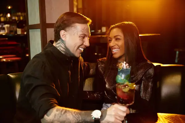 Zwei junge Erwachsene genießen einen fröhlichen Abend an einer Bar, teilen Drinks und lächeln gemeinsam. — Stockfoto