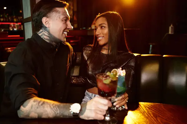 A young couple shares a joyful moment over drinks in a vibrant bar during a night out. — Stock Photo