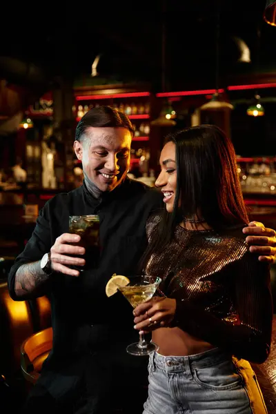 Tattooed couple shares laughter and drinks on a lively evening date at a bar. — Stock Photo