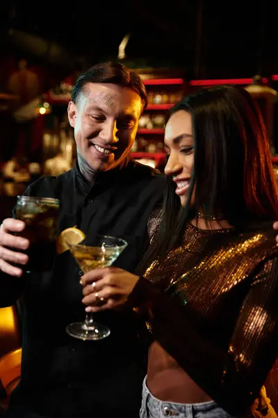 A multicultural couple shares laughter and drinks during a fun evening at the bar. — Stock Photo