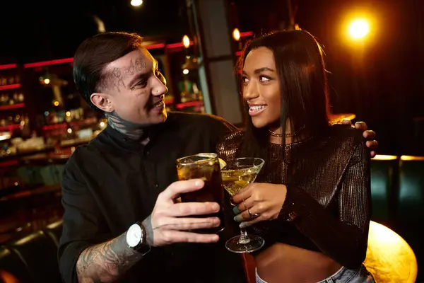 Tattooed man and woman share joyful drinks while on a romantic date at the bar. — Stock Photo