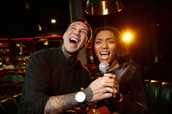 Lively multicultural couple shares a joyful moment on their date while singing at a bar. — Stock Photo