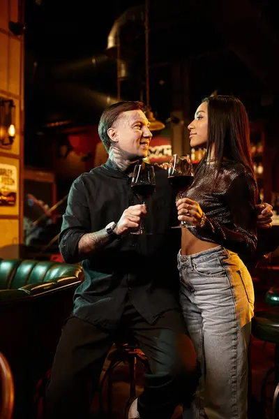 A young couple shares drinks in a cozy bar, celebrating their love and diversity. — Stock Photo