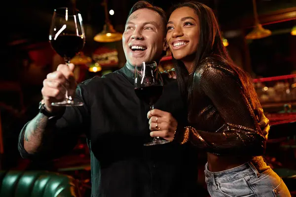 A tattooed couple celebrates their connection over drinks in a lively nightlife setting. — Stock Photo