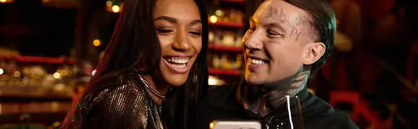 Young couple shares a joyful moment during their night out at a lively bar filled with excitement. — Stock Photo