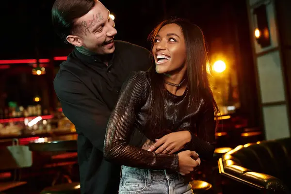 A young couple shares a joyful moment on a date at a lively bar, surrounded by nightlife. — Stock Photo