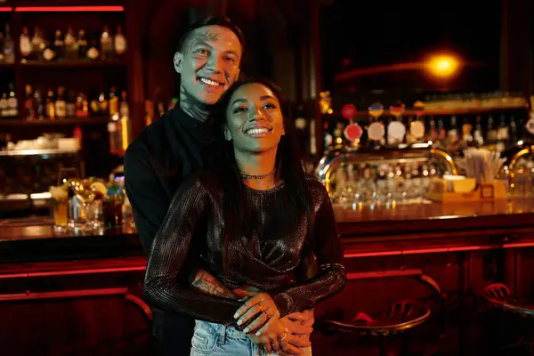 A multicultural couple enjoys a lively evening at a bar, sharing laughter and connection. — Stock Photo