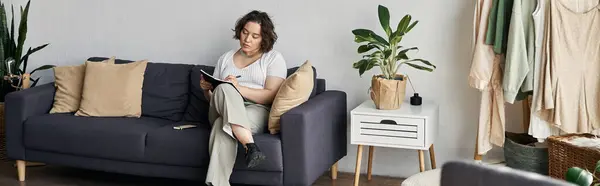 Curly-haired woman relaxes on a couch, journaling in her beautiful, airy living space, banner — Stock Photo
