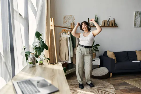 In her stylish apartment, a young woman with curly hair joyfully dances, embracing life. — Stock Photo