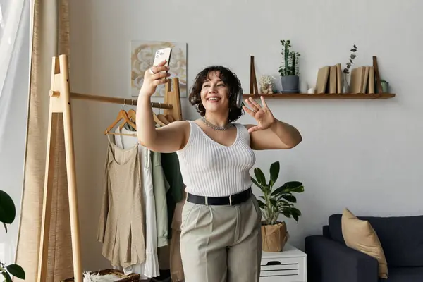 A young woman with curly hair smiles and poses while enjoying a moment in her stylish apartment. — Stock Photo
