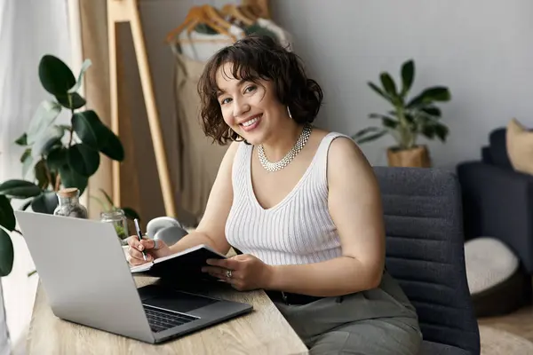 Eine junge Frau mit lockigem Haar genießt ihren Tag in einer stilvollen Wohnung beim Journalismus. — Stockfoto