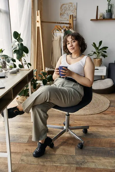 Eine schöne junge Frau mit lockigem Haar entspannt in ihrer modernen Wohnung, während sie Kaffee schlürft. — Stockfoto