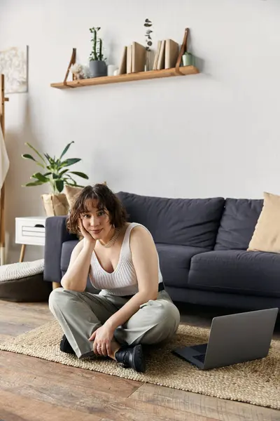 A young woman relaxes on the floor of her stylish apartment, enjoying her daily routine. — Stock Photo