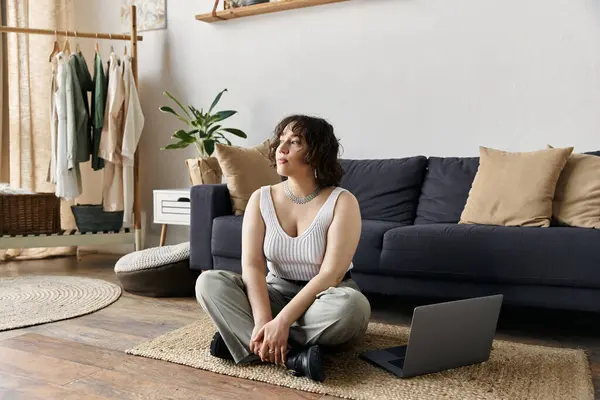 A beautiful woman with curly hair relaxes on the floor of her stylish apartment. — Stock Photo