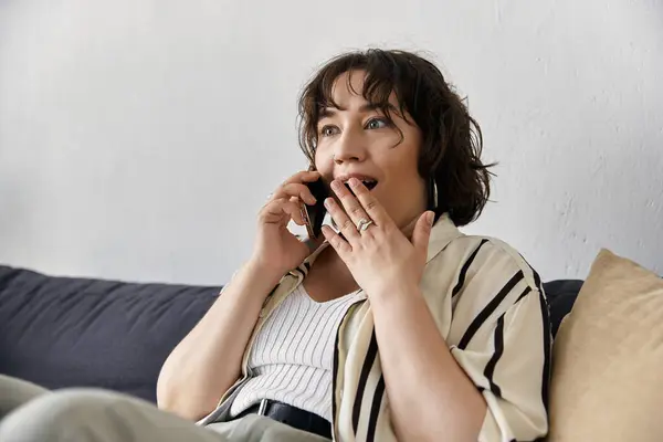 Uma jovem mulher com cabelos encaracolados bate-papos alegremente no telefone em seu aconchegante apartamento. — Fotografia de Stock