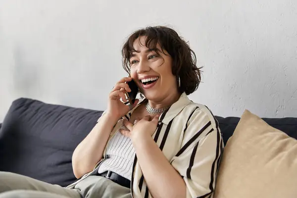 A bright apartment features a young woman happily chatting on her phone. — Stock Photo