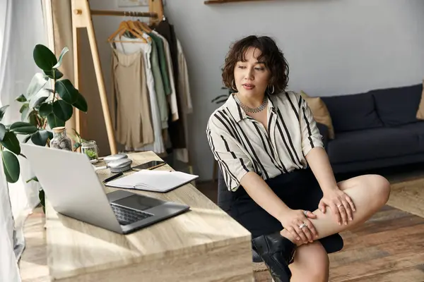 A beautiful young woman with curly hair relaxes in her stylish apartment, engaging with her laptop. — Stock Photo