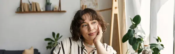 A beautiful young woman with curly hair relaxes in her stylish loft, banner — Stock Photo