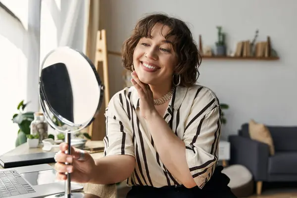 A young woman with curly hair enjoys her time in a modern apartment, engaging with a mirror. — Stock Photo