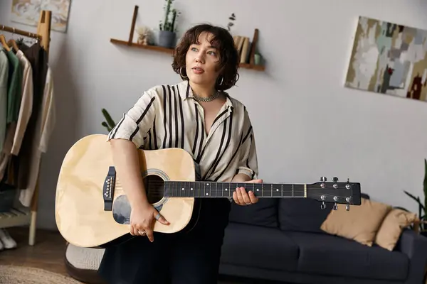 Beautiful woman plays guitar in her stylish apartment, embracing her artistic lifestyle. — Stock Photo