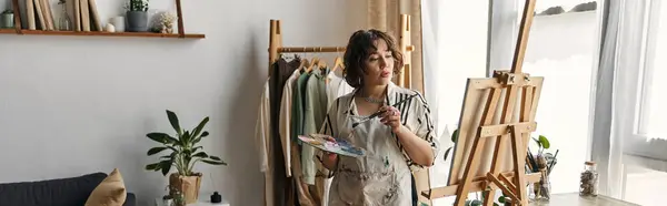 A young woman with curly hair immerses herself in painting, expressing her artistic talent, banner — Stock Photo