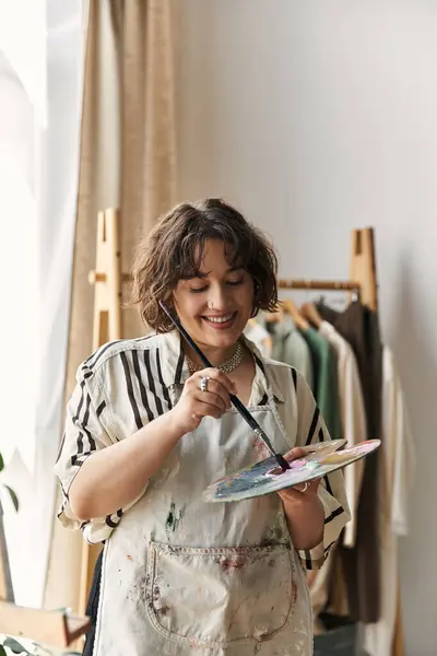 Joyful artist engages with her paintbrush, capturing creativity in a bright apartment. — Stock Photo