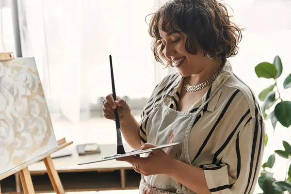 A joyful artist paints in her bright, modern apartment full of creativity. — Stock Photo