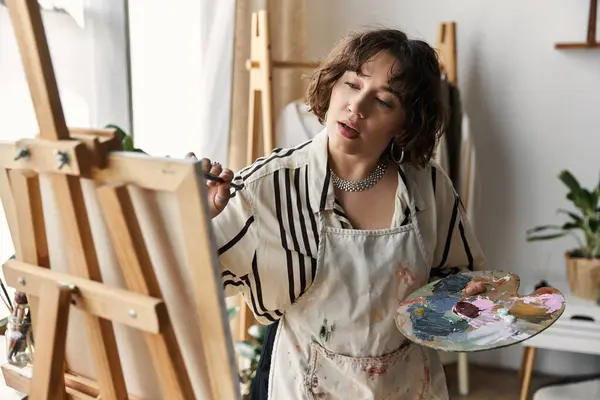 A talented young woman with curly hair focuses on her art, creating a beautiful masterpiece. — Stock Photo