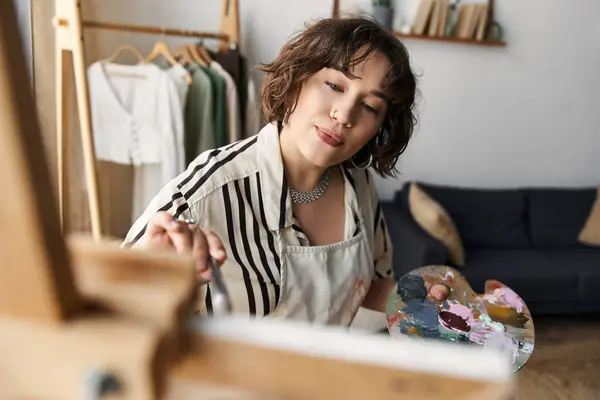 En un apartamento elegante, una joven con el pelo rizado muestra su talento para pintar. — Stock Photo