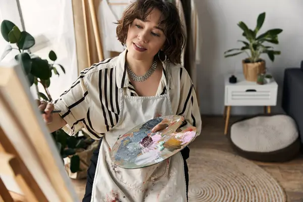 In a bright modern apartment, a young woman with curly hair immerses herself in painting art. — Stock Photo
