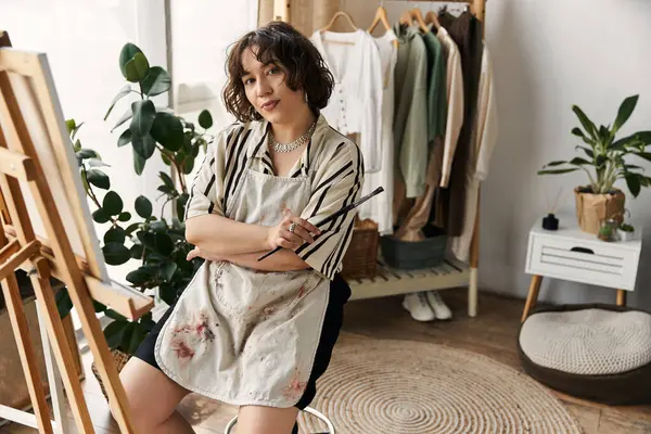 In a bright apartment, a talented young woman with curly hair engages in painting with a brush. — Stock Photo