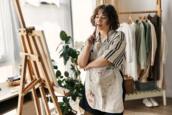 Curly-haired artist focuses on her canvas while surrounded by a modern apartment setup. — Stock Photo