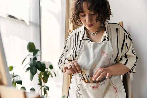 A talented young artist with curly hair passionately paints while nestled in her stylish apartment. — Stock Photo