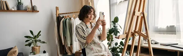 A talented young woman with curly hair passionately paints in her stylish apartment, banner — Stock Photo