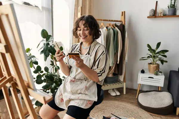 A talented young woman happily paints in her stylish, sunlit apartment. — Stock Photo