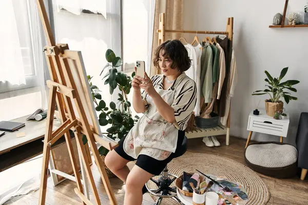 A young woman with curly hair captures her artistic process in a modern apartment during the day. — Stock Photo