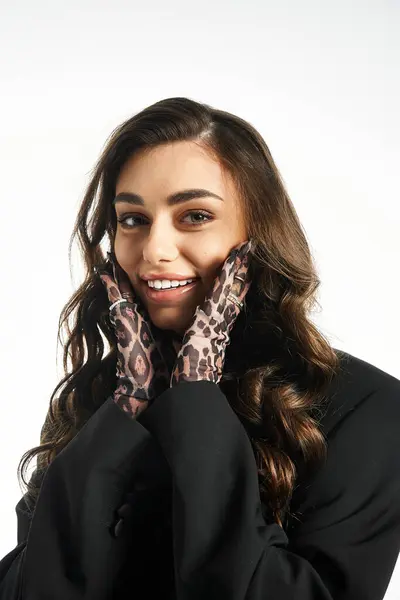 Young woman smiles cheerfully while highlighting stylish gloves in a creative fashion studio. — Stock Photo