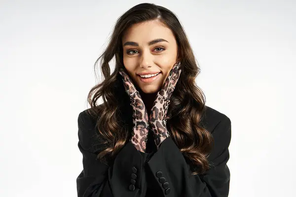 A trendy young woman showcases her playful side with stylish gloves and a radiant smile. — Stock Photo