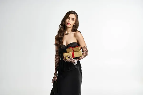 Glamorous young woman holds beautifully wrapped gifts while showcasing elegant fashion. — Stock Photo