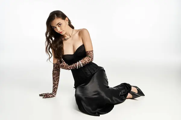 Young woman showcases grace and fashion in a stunning black dress and animal print gloves. — Stock Photo
