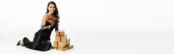 Cheerful young woman in elegant attire poses with beautifully wrapped gifts for a celebration. — Stock Photo