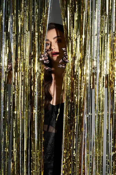 A young woman stands behind glittering curtains, radiating confidence and playfulness. — Stock Photo
