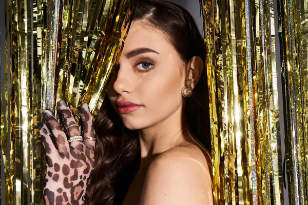 Captivating young woman showcases her charm with stylish attire near golden decorations — Stock Photo