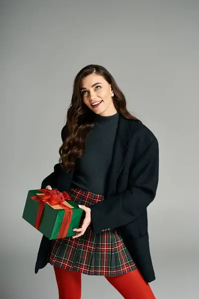 Brightly smiling woman showcases a beautifully wrapped present in holiday fashion. — Stock Photo