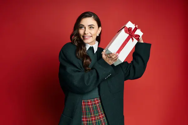 Bright smile on a young woman holding a present, radiating holiday spirit and joy. — Stock Photo