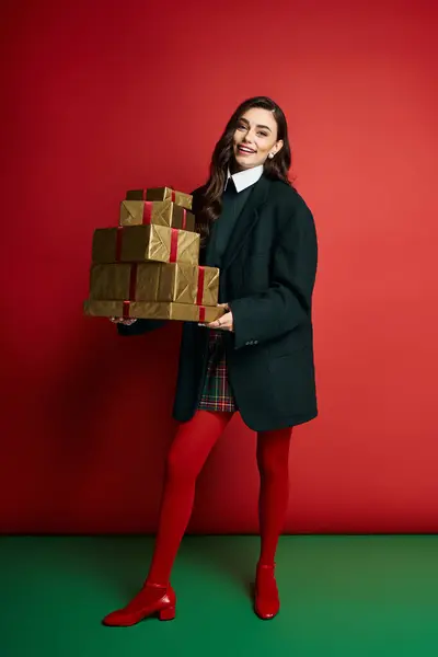 Femme joyeuse dans des vêtements élégants porte des cadeaux enveloppés, exsudant l'esprit de vacances. — Photo de stock