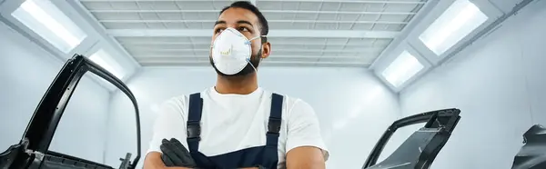Handsome mechanic stands confidently with arms crossed in a clean, bright workshop setting. — Stock Photo